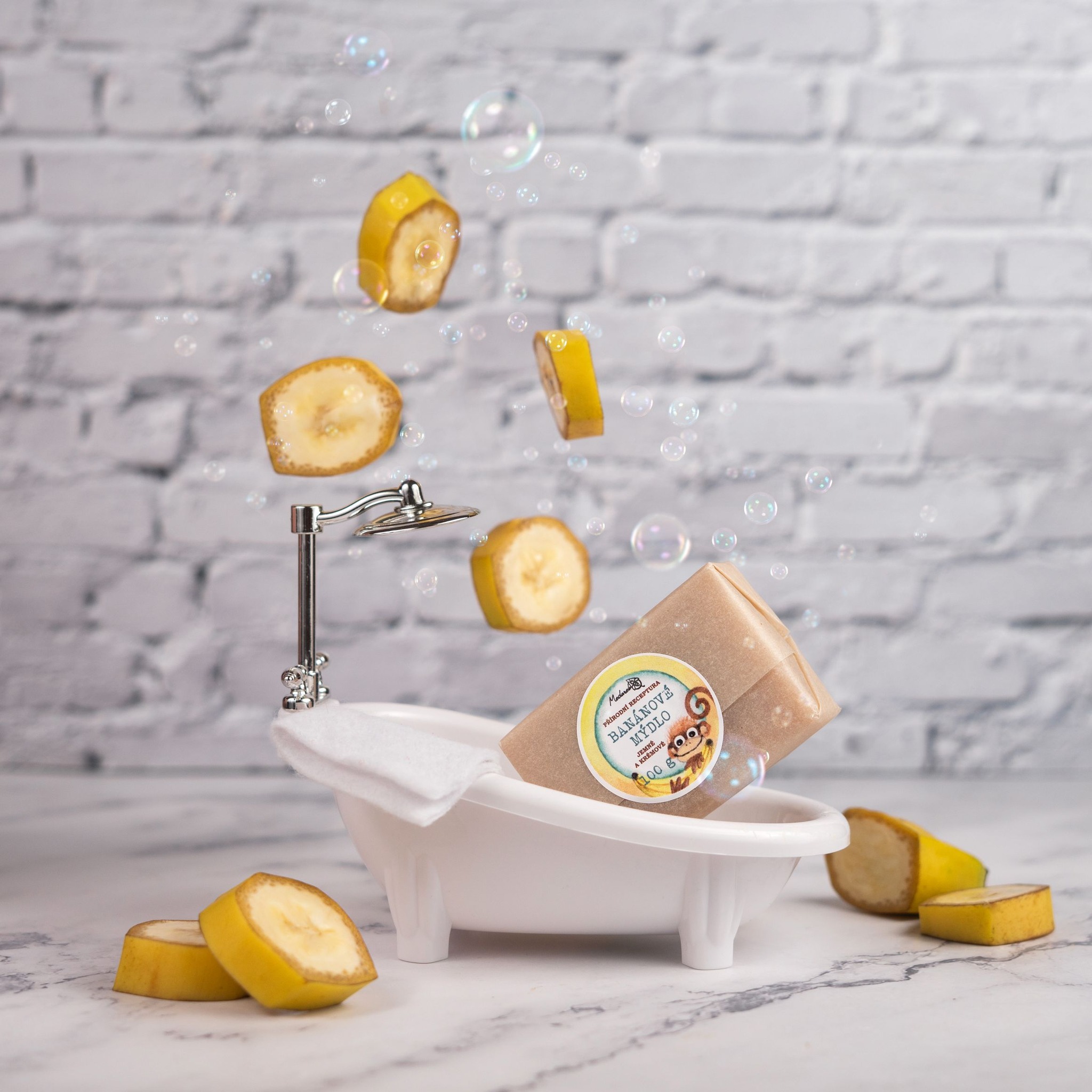 Medarek Banana Soap bar in a tiny bathtub, with floating banana slices and bubbles